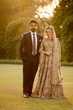 Omer Malik and his wife standing outside; Omer is in a suit and his wife is in a dress.