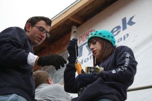 Addison Johnson, a senior studying accounting, and Emily Wood, a junior in the same program, arrange tools and wrap the home in Tyvek paper before nailing siding.