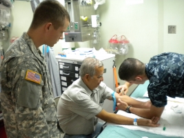 Cadet Daniel Cox stands by to interpret for a patient who is being helped by medical personnel.