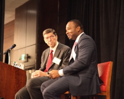 Clayton Christensen and Efosa Ojomo lecture at a conference.