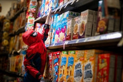 A child dressed as Spider-Man reaches for a box of cereal