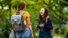 A female student laughs while talking to a friend on campus.