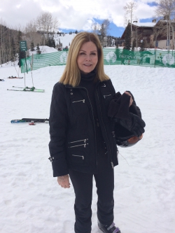 Mary Kay Lloyd standing in front of the snowy ski slopes at Deer Valley Resort while wearing her ski gear.