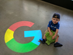 A little baby boy by the Google G with a Google hat on.